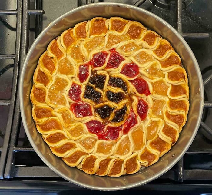 A vibrant pie with swirled pumpkin, apple, and cherry fillings, perfect for sharing.