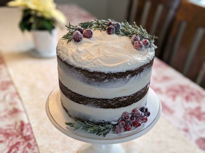 A festive layered cake with creamy frosting and sugared cranberries, perfect for the holidays.