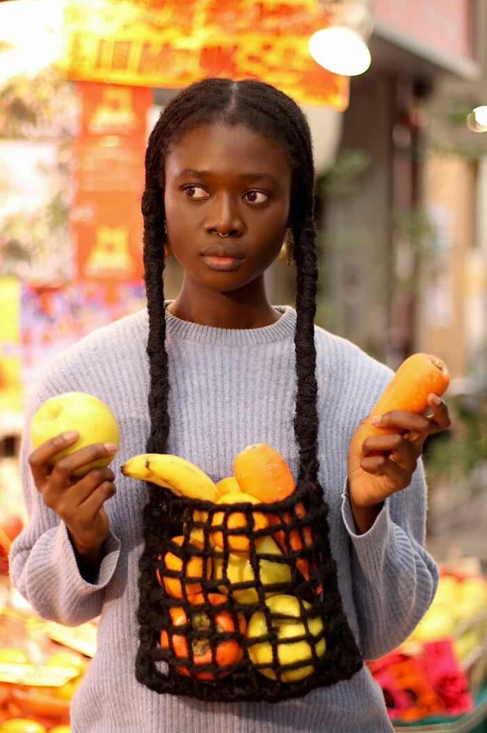 Hair sculpture of a net bag brimming with colorful fruit.