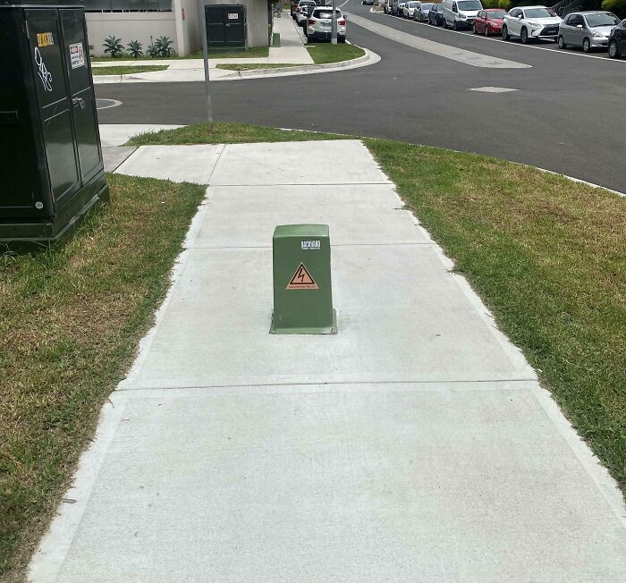 Sidewalk blocked by a dangerous design electrical box in the middle creating a potential death trap for pedestrians.