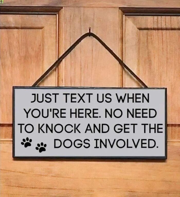 A wooden door with a funny sign asking visitors to text instead of knock to avoid waking the dogs!