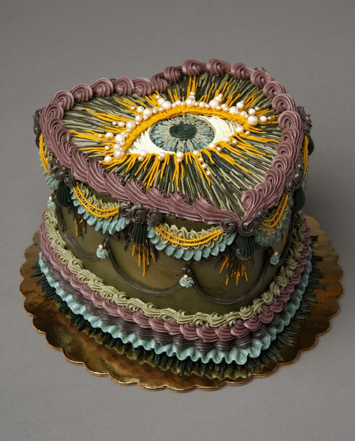 A vibrant vegan cake with colorful swirls and a striking eye motif on top.