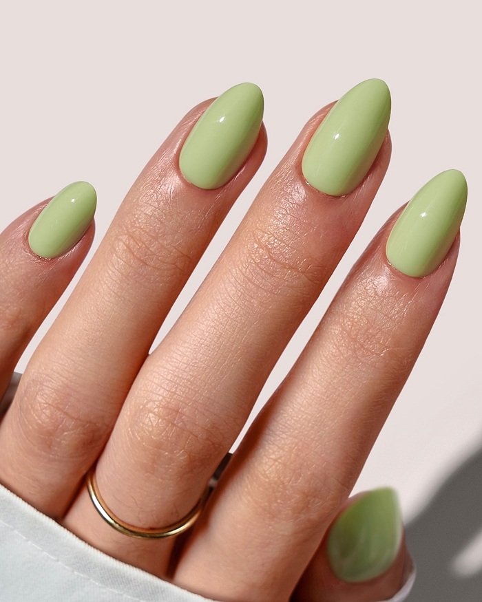 Hand with mint green polished nails showcasing trendy summer nails style for 2025 with silver star and bead ring.
