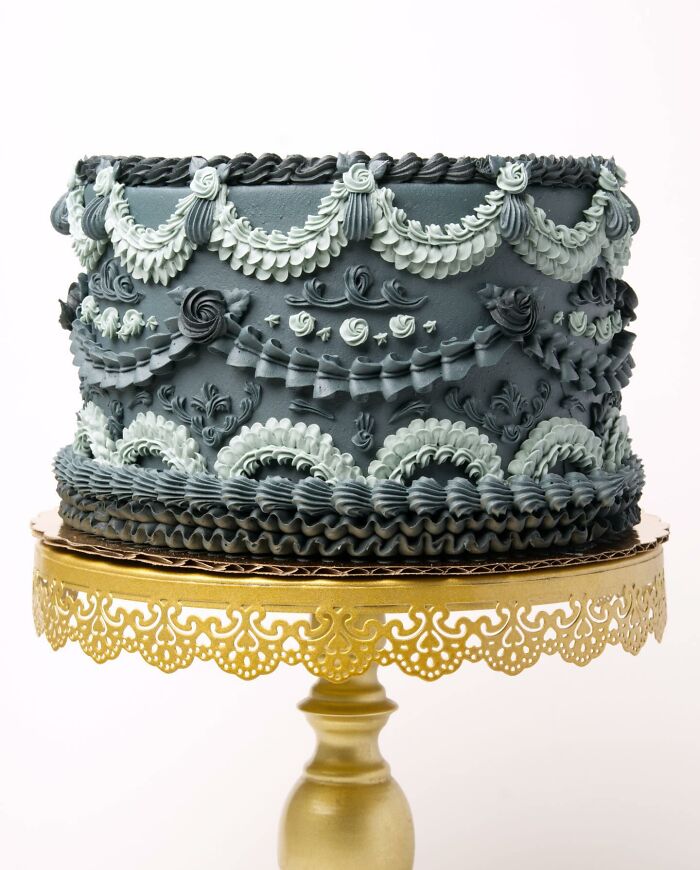 A dazzling vegan cake with ornate icing, proudly displayed on a golden stand.