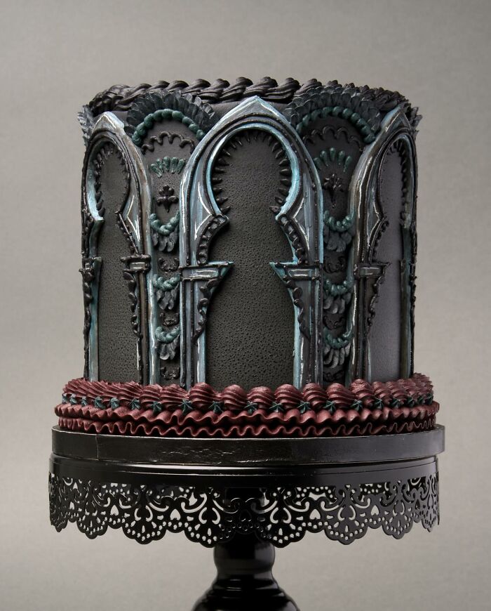 A striking vegan cake with elegant gothic arches, displayed on a decorative stand.