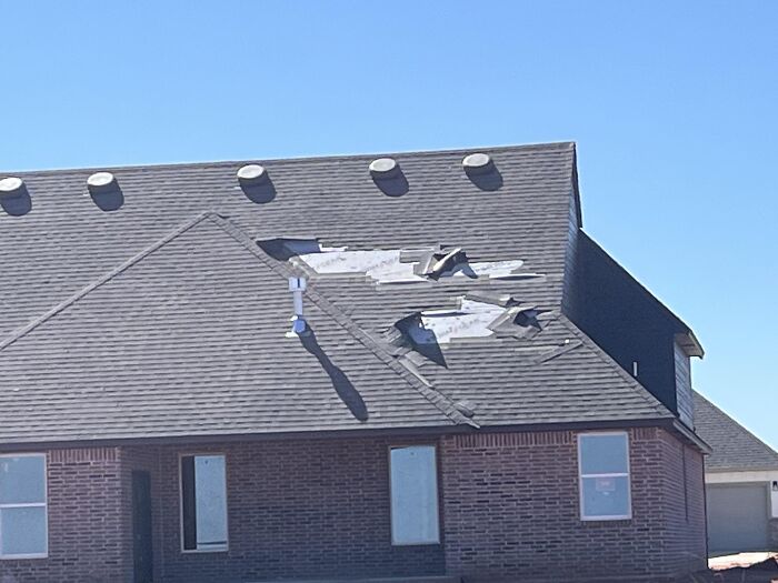 Damaged roof with missing and torn shingles showing unexpected fails in a residential home repair scene.