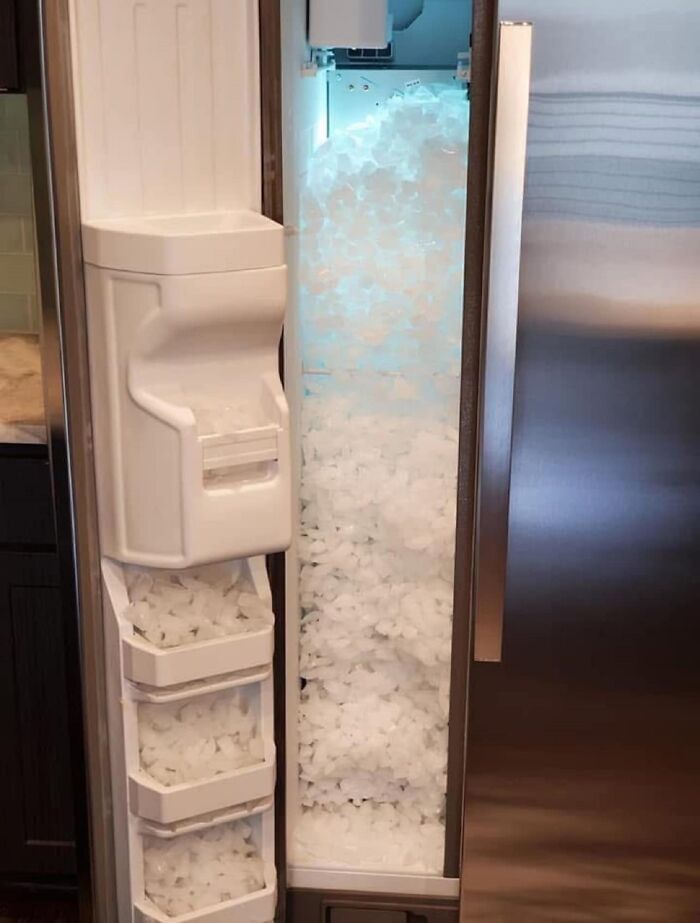 Refrigerator ice dispenser overflowing with ice cubes, showing an unexpected fail of appliance malfunction.