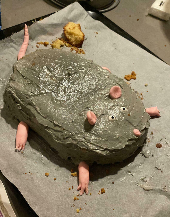 A gray cake shaped like a rat with pink fondant limbs and ears, a hilarious cooking fail.