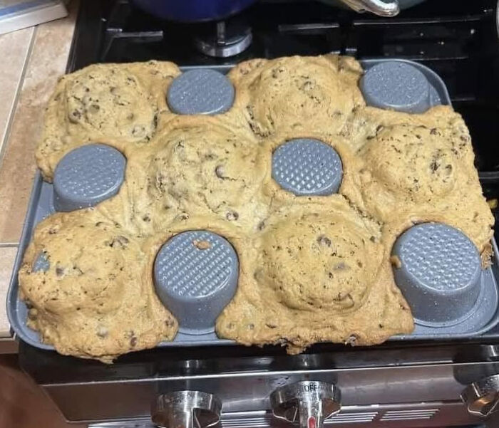 Overfilled muffin pan with gooey cookie dough spilling over, showing a hilarious kitchen accident.