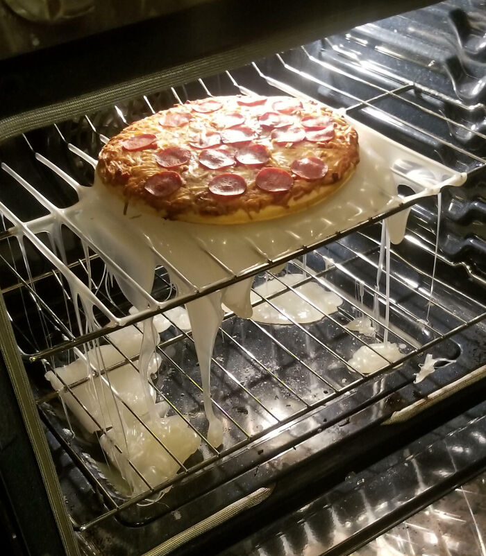 Pepperoni pizza baking with a melted plastic sheet in the oven, a funny cooking fail.