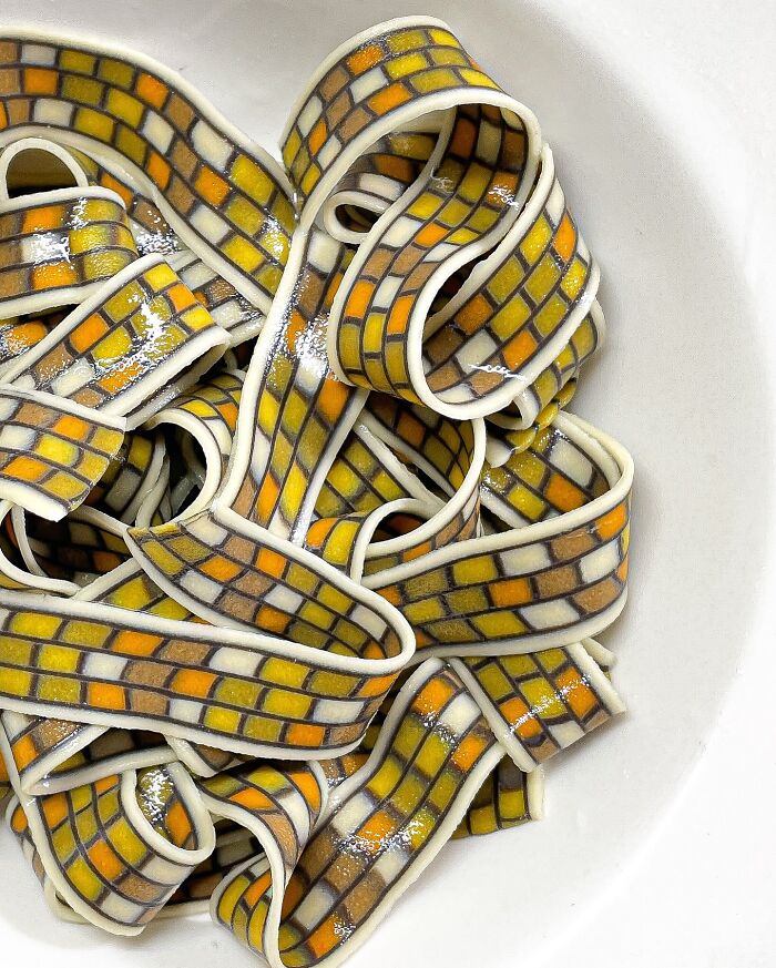 Handcrafted pasta with vibrant mosaic patterns in a white bowl, showcasing culinary artistry. Handcrafted pasta with vibrant mosaic patterns in a white bowl, showcasing culinary artistry.