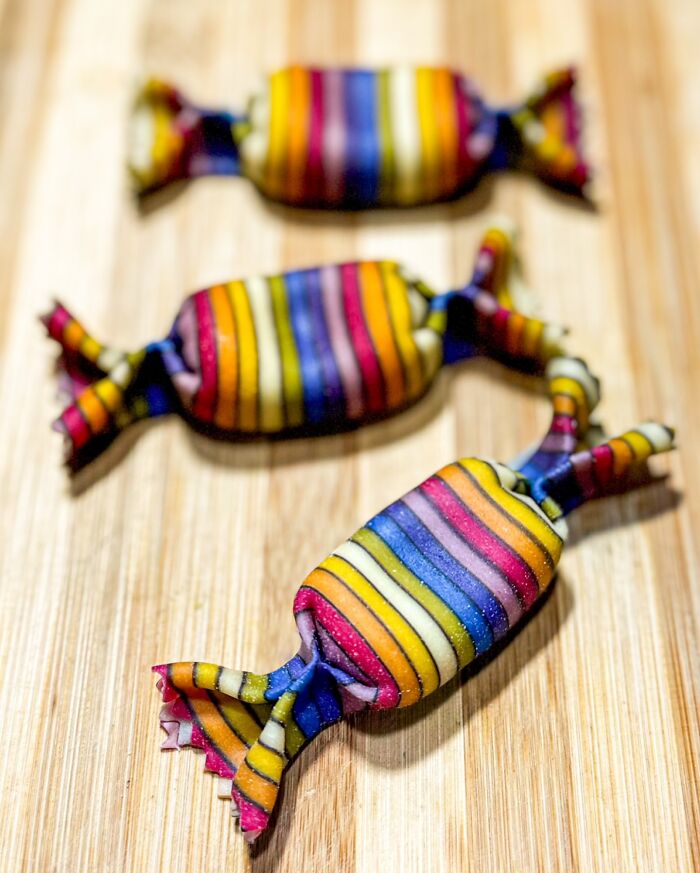Colorful handcrafted pasta with vibrant stripes, resembling candy, on a wooden board by a culinary artist. Colorful handcrafted pasta with vibrant stripes, resembling candy, on a wooden board by a culinary artist.