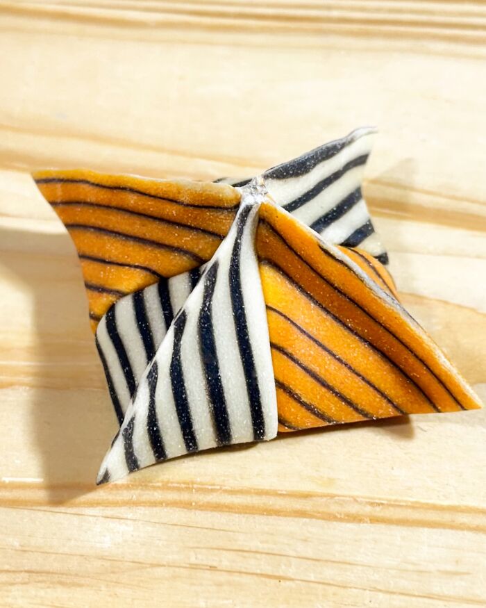 Colorful handcrafted pasta with orange and black stripes on a wooden surface, showcasing culinary artistry. Colorful handcrafted pasta with orange and black stripes on a wooden surface, showcasing culinary artistry.