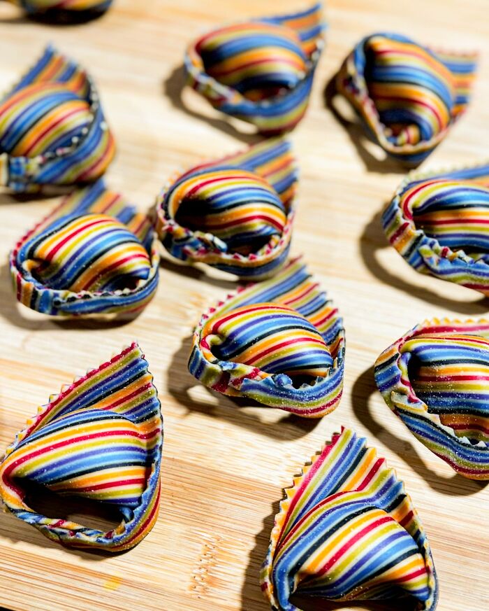 Handcrafted pasta with colorful patterns on a wooden board, showcasing culinary artistry. Handcrafted pasta with colorful patterns on a wooden board, showcasing culinary artistry.
