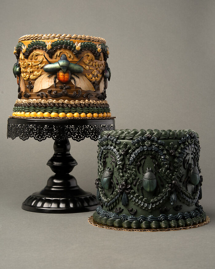 Two quirky vegan cakes topped with lifelike bugs and slugs, displayed on sleek black stands.