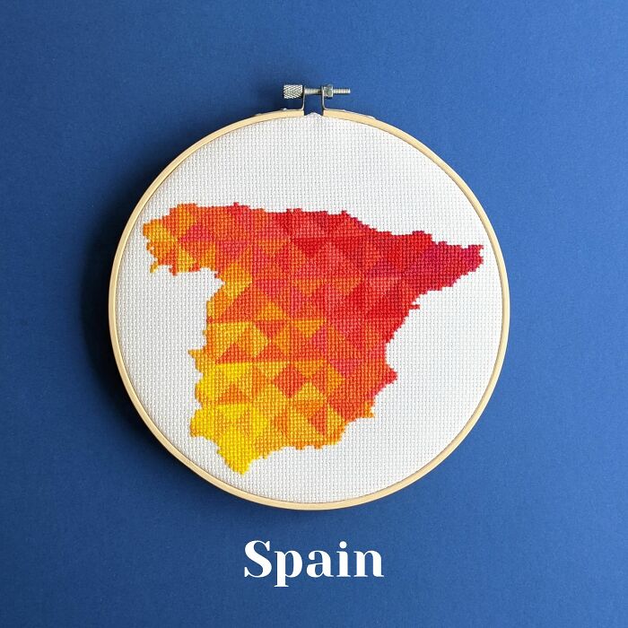 Spain’s map in warm gradient hues, stitched with flair and framed in a hoop on a blue background.