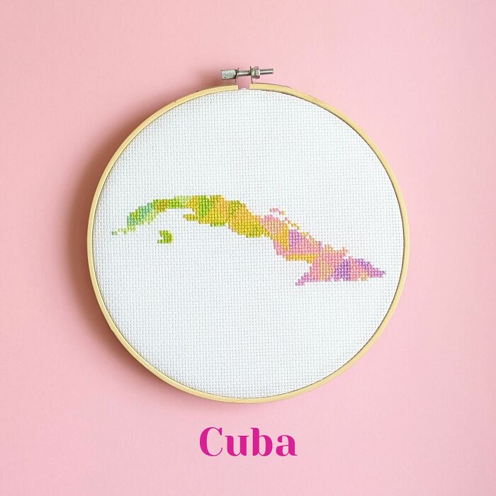 Cuba’s map bursts with vibrant colors, stitched with flair and framed in a hoop on a lively pink background.