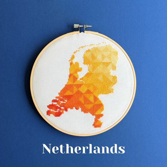 Netherlands’ map in warm orange hues, stitched with care and framed in a hoop on a blue background.