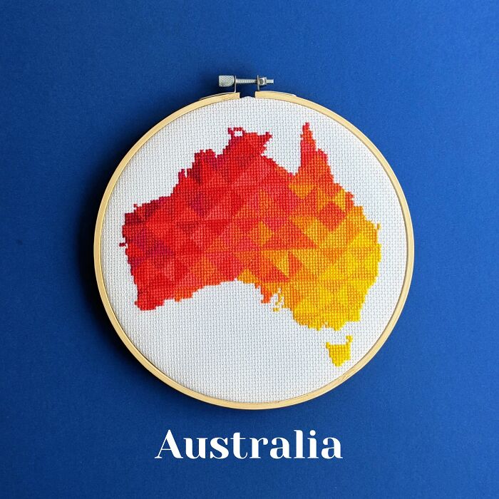 Australia’s map in warm reds and yellows, stitched with energy and framed in a hoop on a blue background.