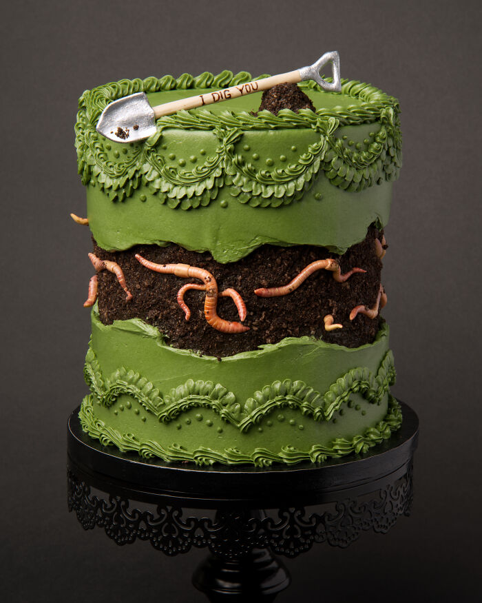 A fun vegan cake with edible worms, green frosting, and a tiny shovel for a bug-themed delight.